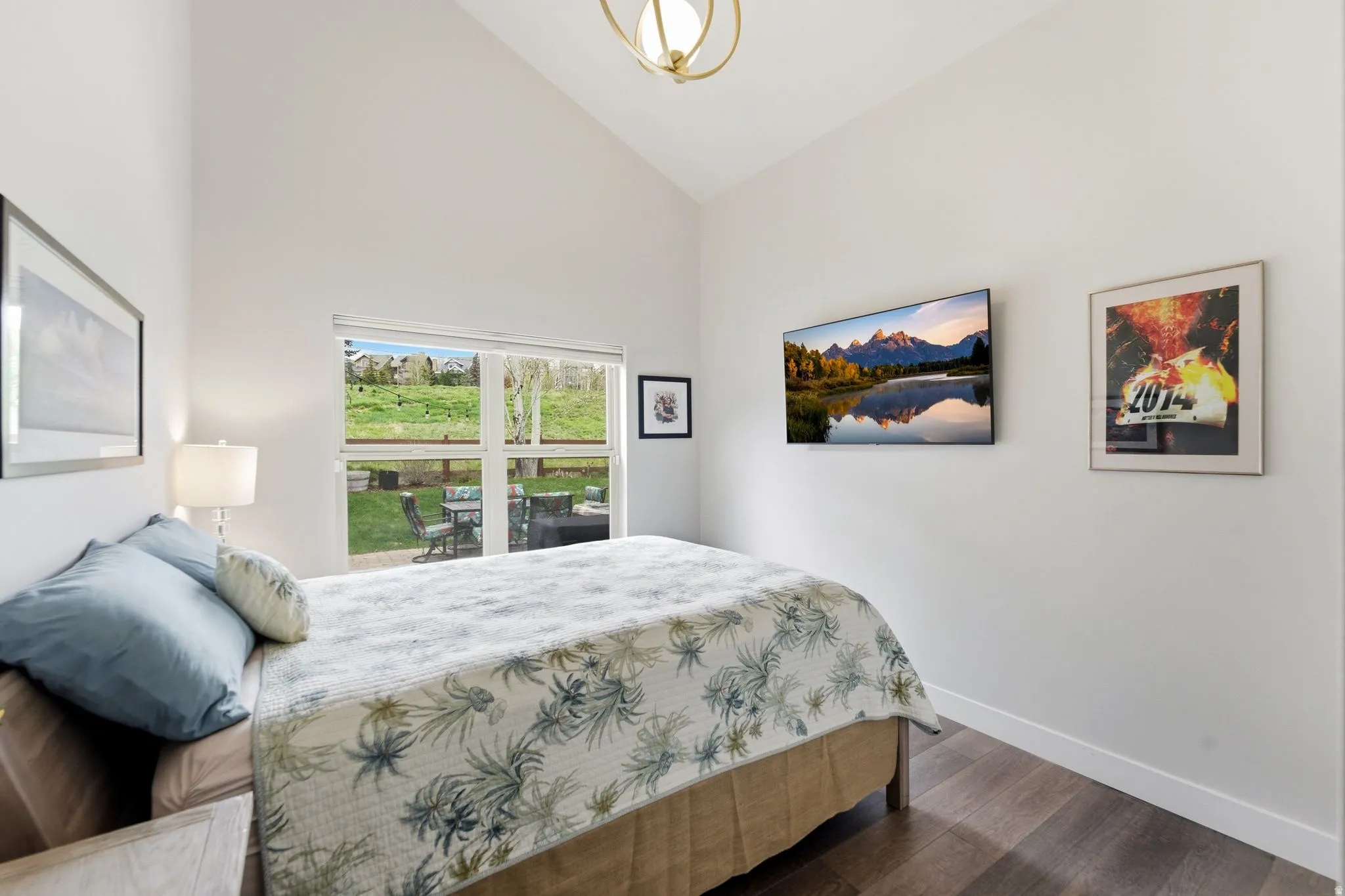 Bedroom with vaulted ceiling, dark wood-style flooring, and hanging lights