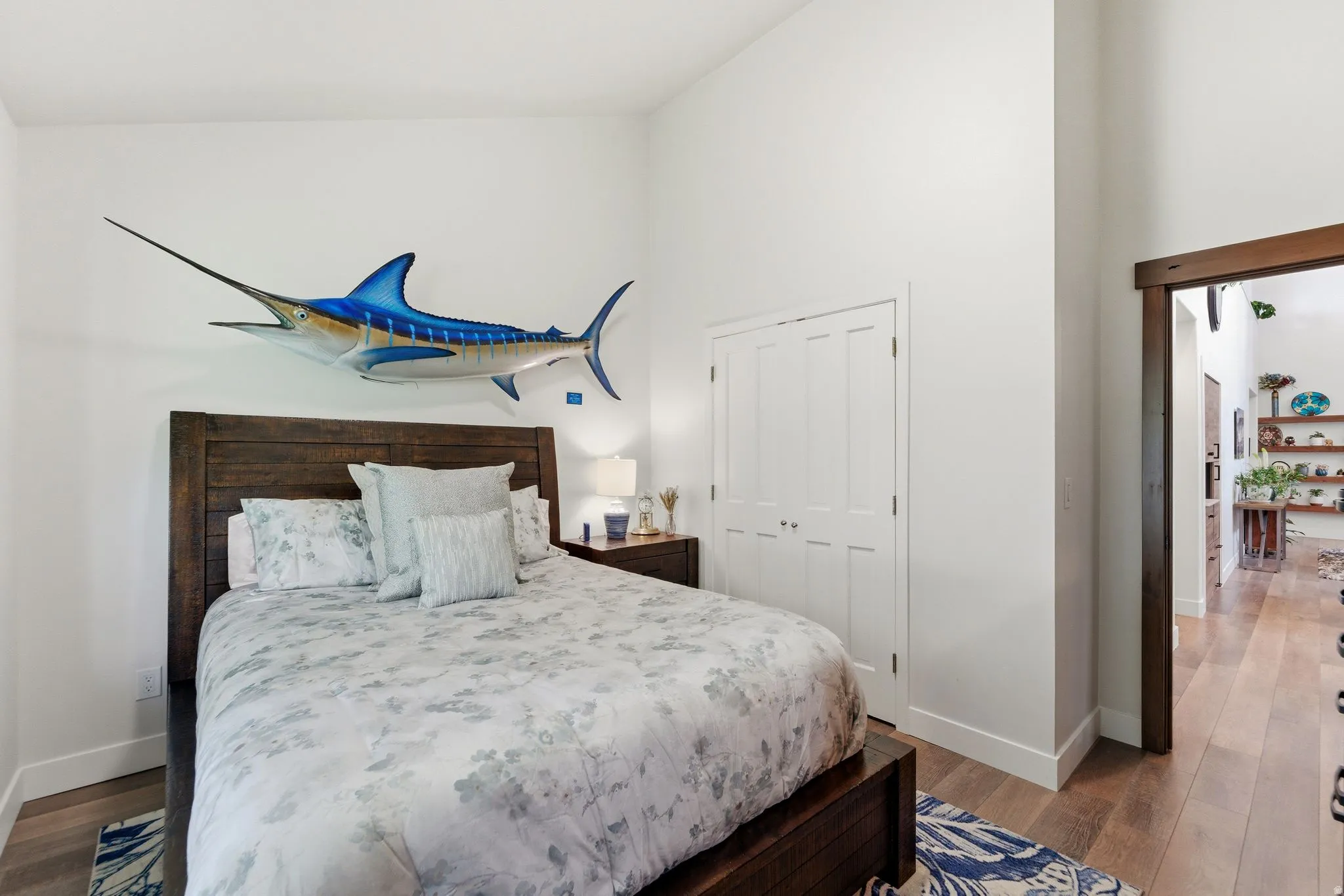 Bedroom with light wood-type flooring, a high ceiling, and a closet