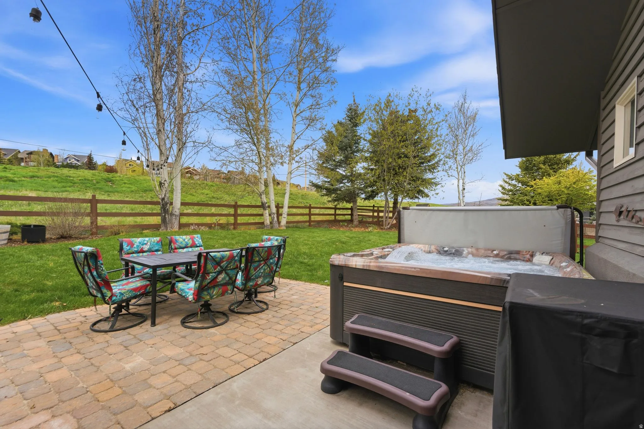 Fenced backyard with outdoor dining area, a patio, and a hot tub
