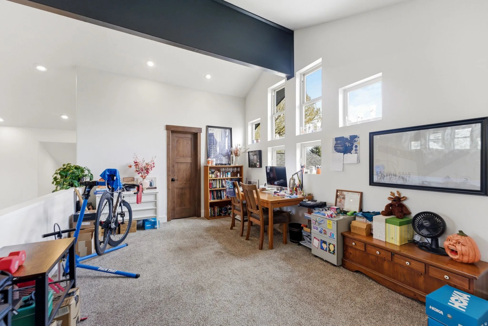 Home office with light carpet and vaulted ceiling