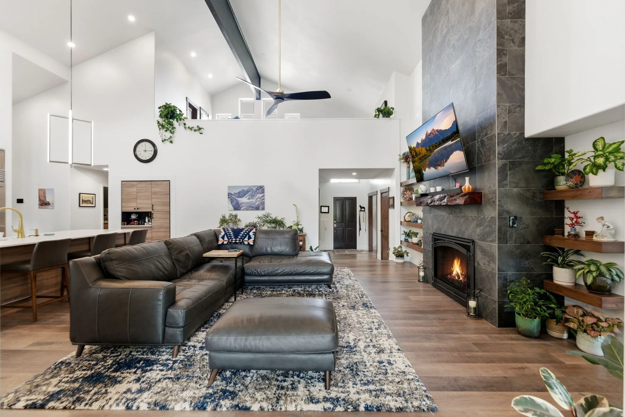 Living room with a tiled fireplace, wood finished floors, and ceiling fan