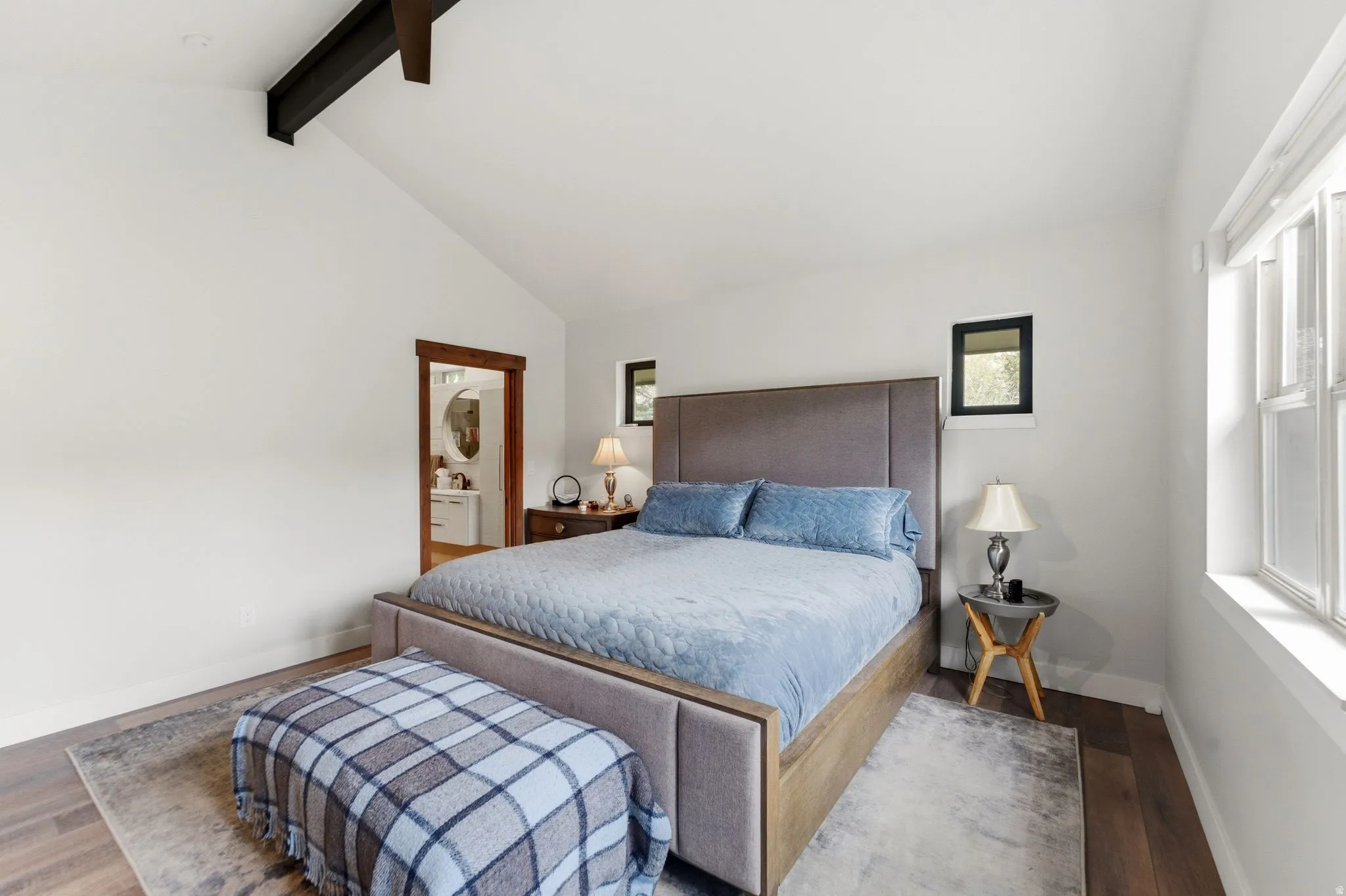 Bedroom with wood finished floors, beam ceiling, and ensuite bath