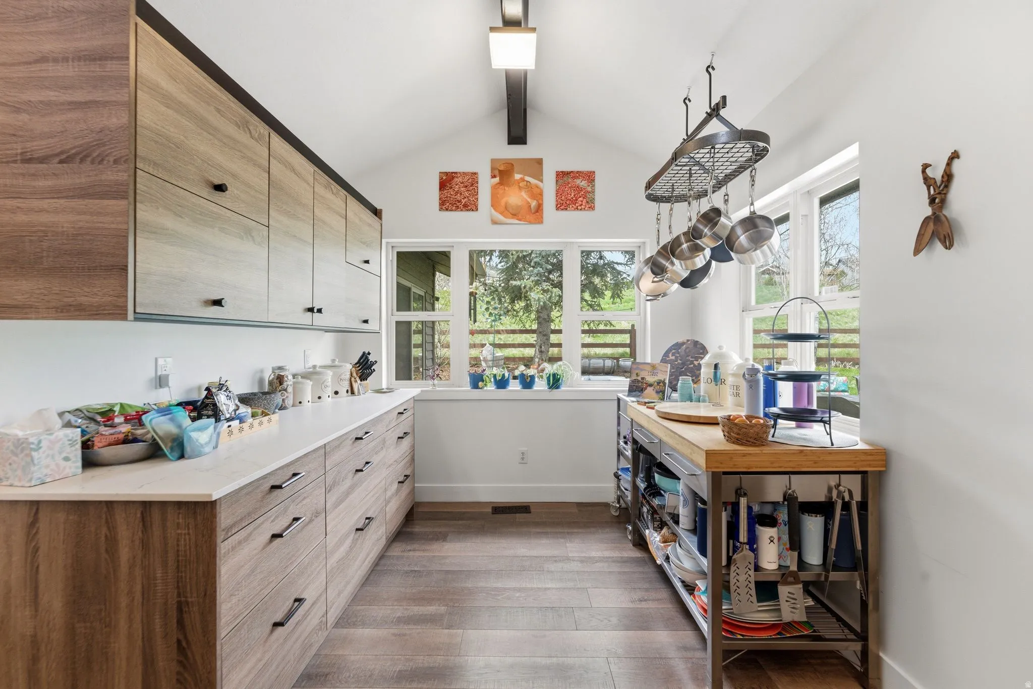 Kitchen with dark wood-type flooring, healthy amount of natural light, beam ceiling, modern cabinets, and light wood finish cabinetry