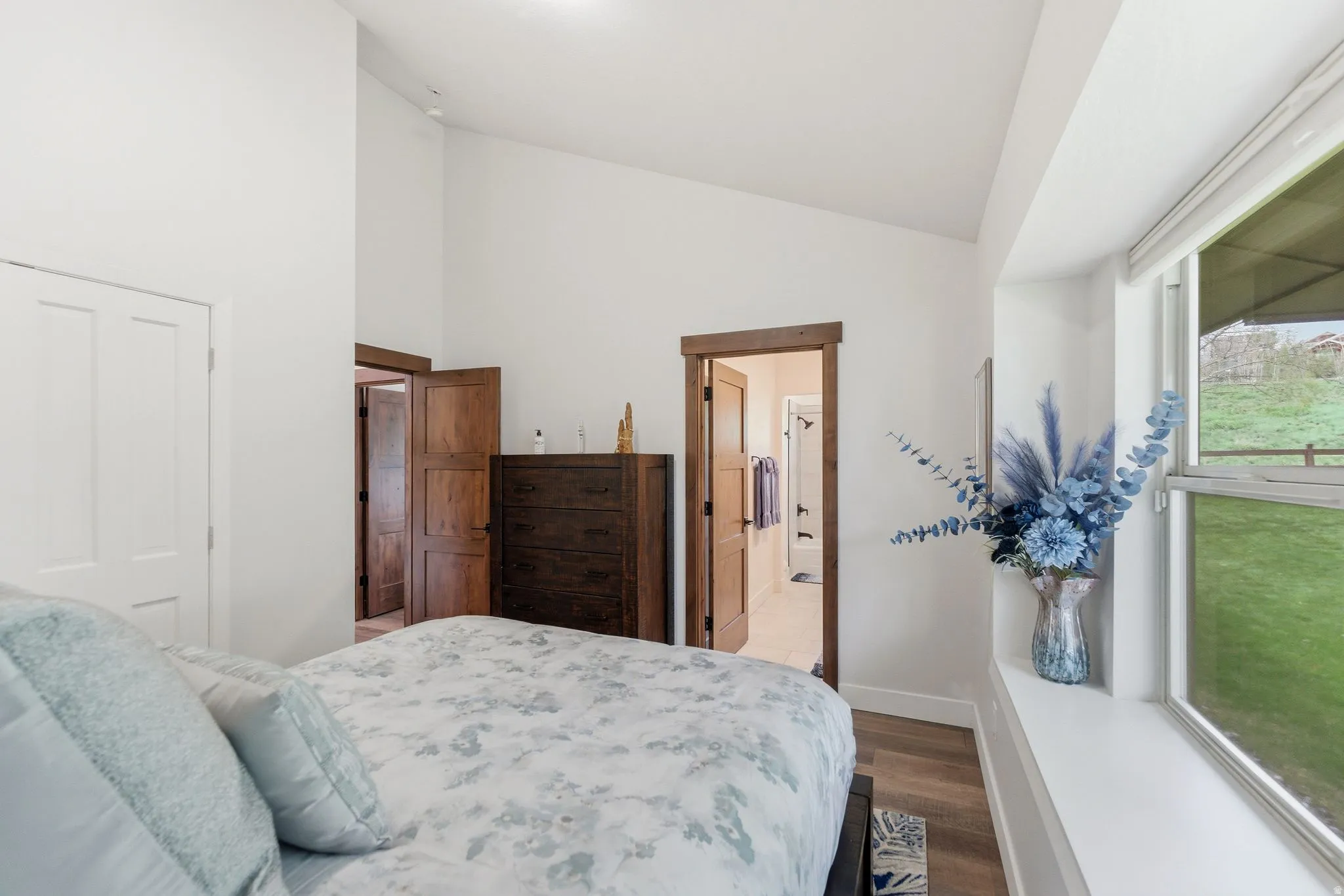 Bedroom with lofted ceiling, dark wood finished floors, and ensuite bath