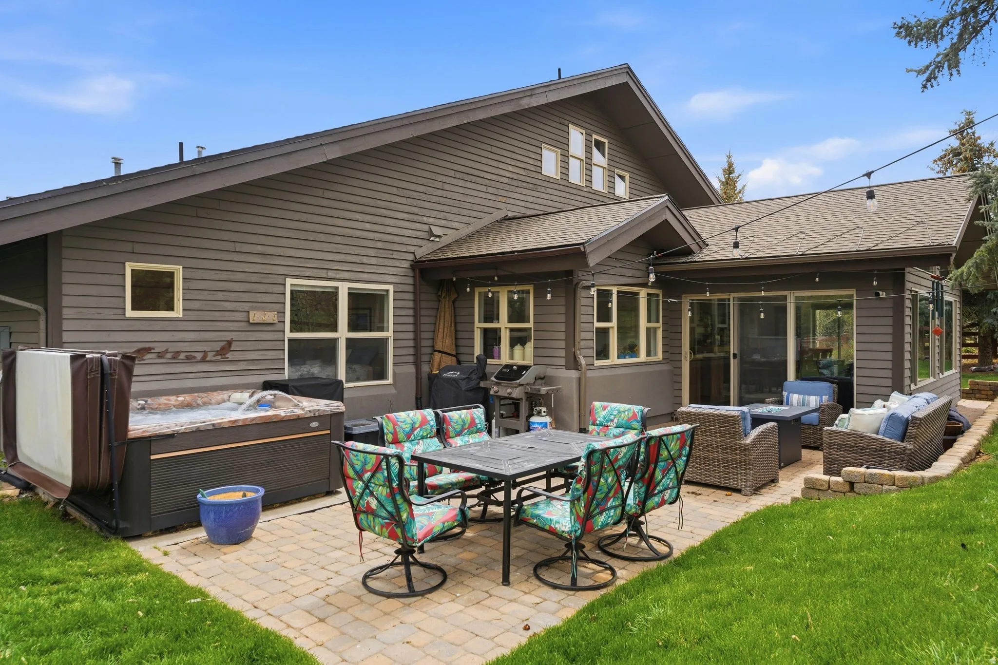 Back of property featuring a hot tub, a patio, roof with shingles, outdoor lounge area, and a yard