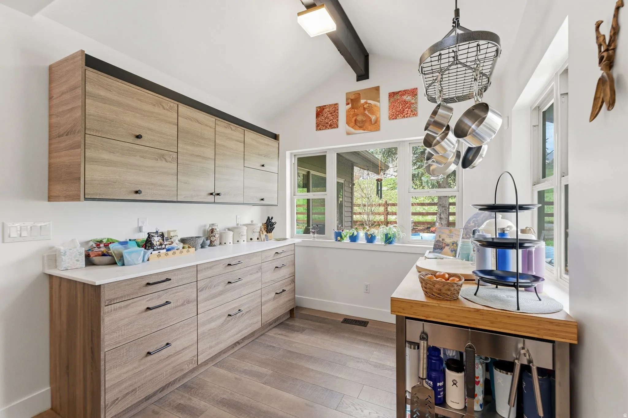 Kitchen with light wood finish cabinetry, light wood-style flooring, modern cabinets, and lofted ceiling with beams