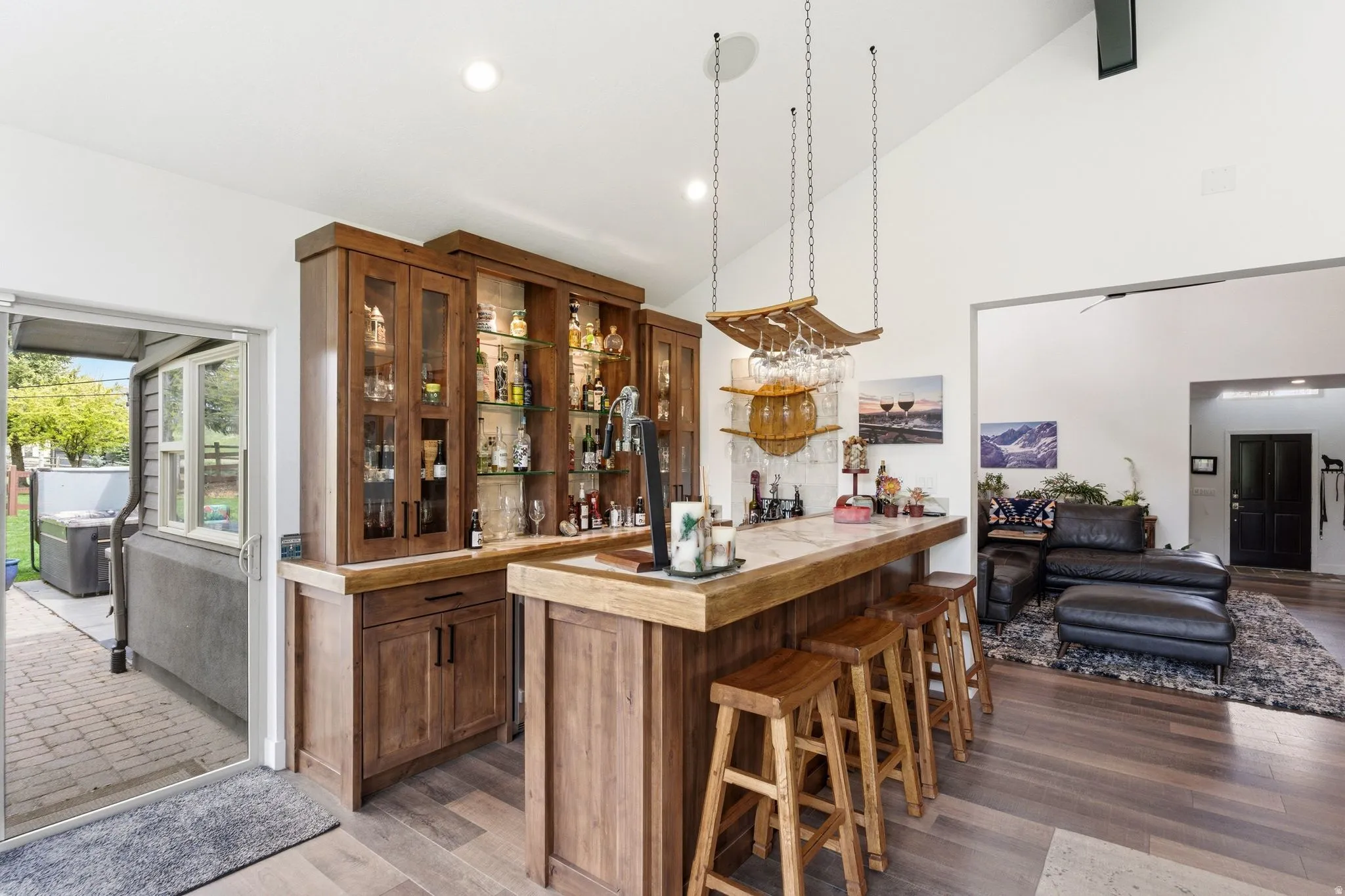 Indoor bar with open shelves, vaulted ceiling, glass fronted cabinets, light wood finished floors, and wooden counters