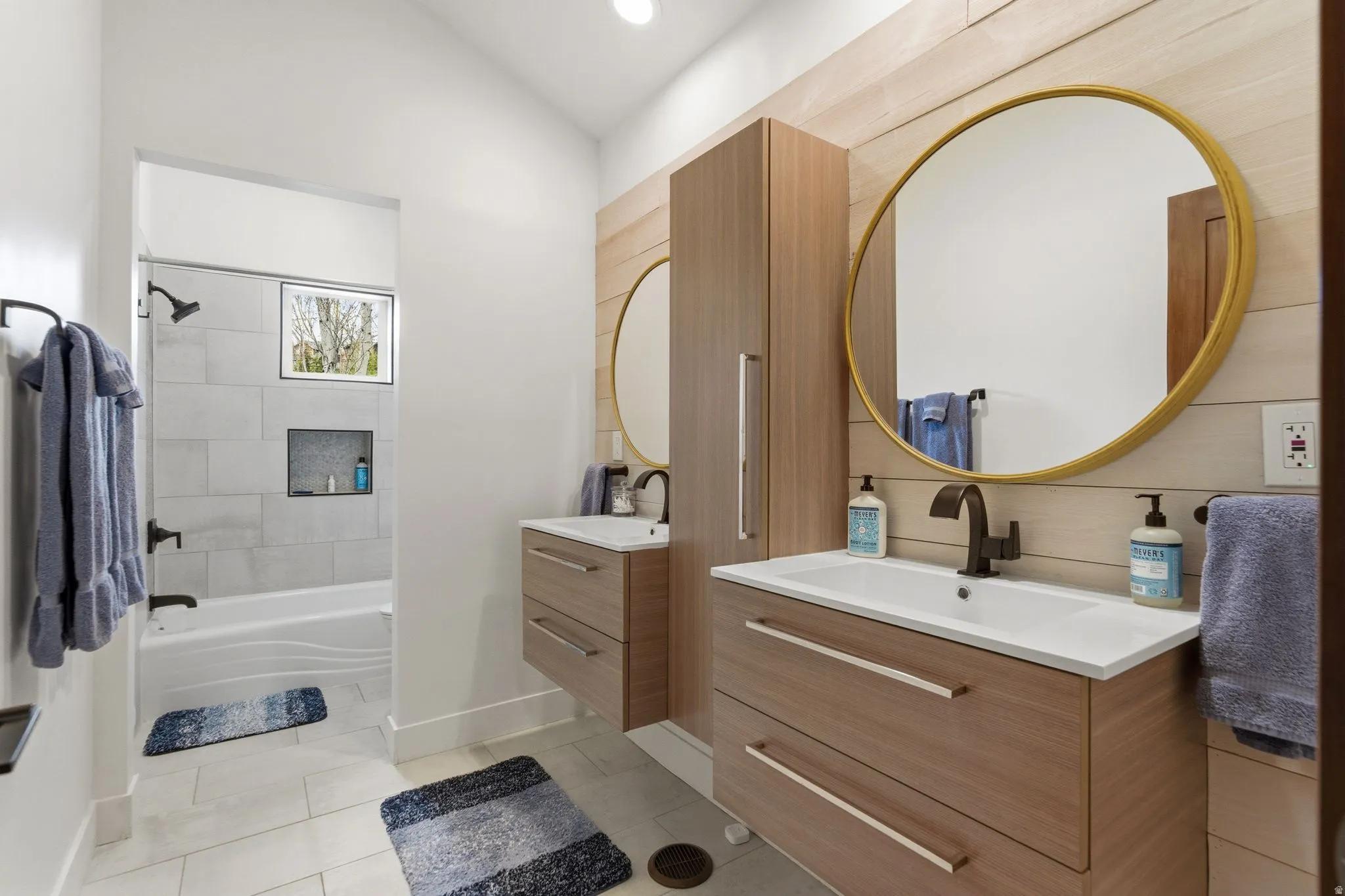 Bathroom featuring two vanities, light tile patterned flooring, shower / bath combination, and recessed lighting