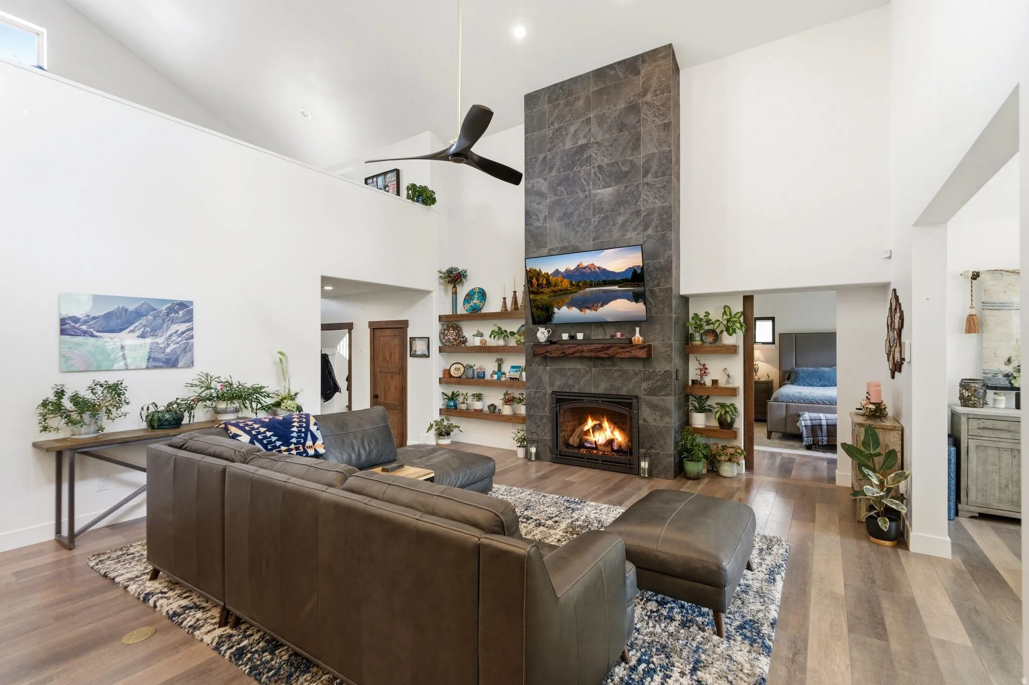 Living area with a tile fireplace, wood finished floors, vaulted ceiling, and a ceiling fan