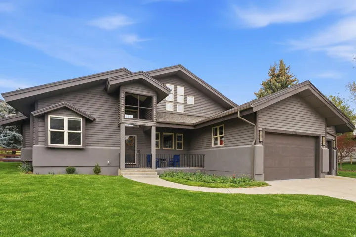 View of front of home with a front lawn, an attached garage, concrete driveway, and covered porch