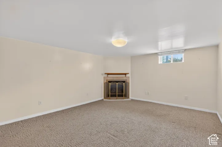 Below grade area featuring a tile fireplace and carpet flooring