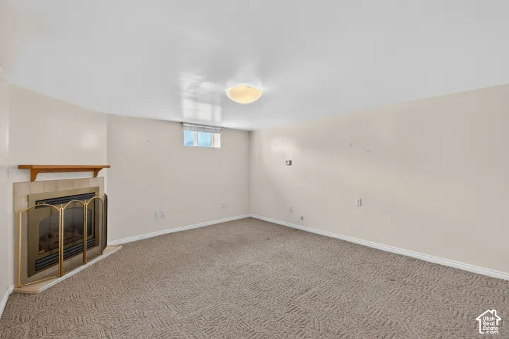 Basement with a tiled fireplace and carpet floors