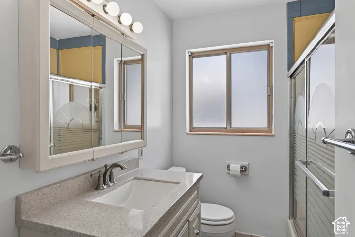 Bathroom vanity featuring a light speckled countertop, undermount sink, and brushed nickel faucet