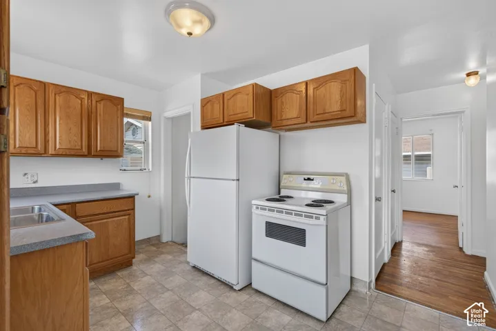 Kitchen featuring wood cabinetry, a stainless steel sink, a full-size refrigerator, an electric range, and resilient flooring