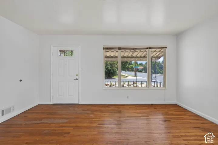 Living area featuring wood-finish flooring, white walls, and a large bay window