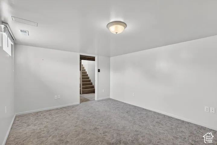 Empty room with light colored carpet and stairway