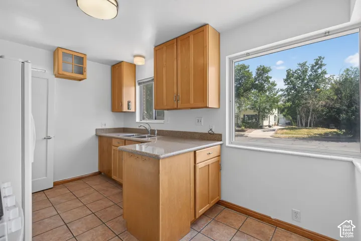 Kitchen featuring wood-finish cabinetry, tile flooring, and light-colored countertops