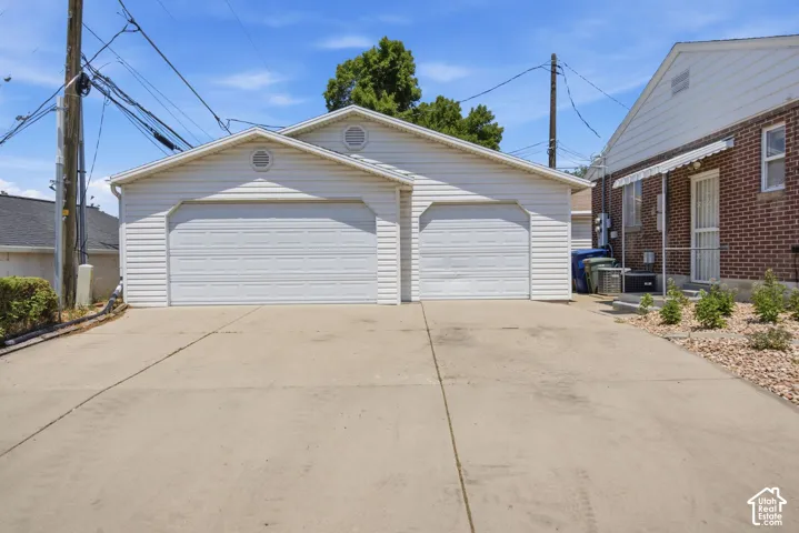 Detached two-car garage with white vinyl siding, two panel garage doors, and a concrete driveway