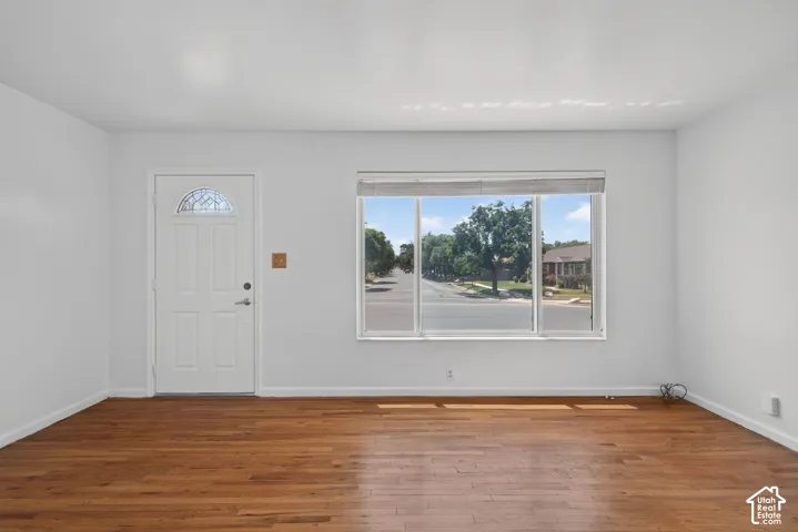 Bright interior space featuring wood-finish flooring, white walls, and a large picture window