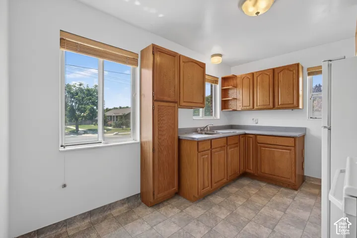Kitchen featuring wood-finish cabinetry, laminate countertops, and a stainless steel sink with a window overhead