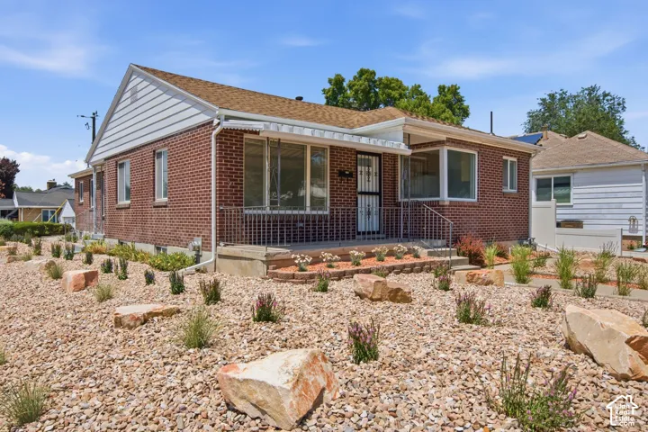 Brick exterior home with white siding accents and a pitched shingle roof