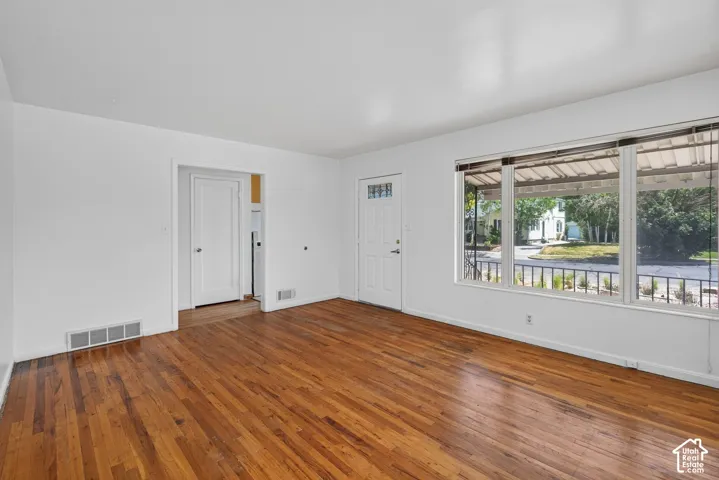 Spacious room featuring wood-finish flooring, white walls, and a large multi-pane window