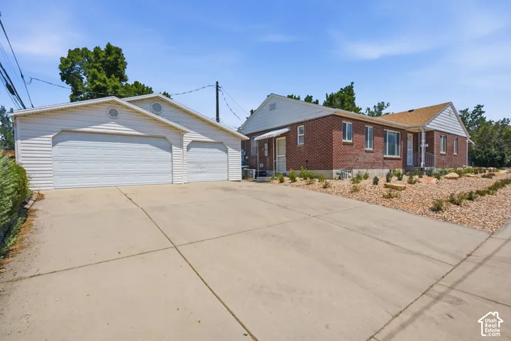 Expansive concrete driveway leading to a detached two-car garage with white vinyl siding and dual overhead doors