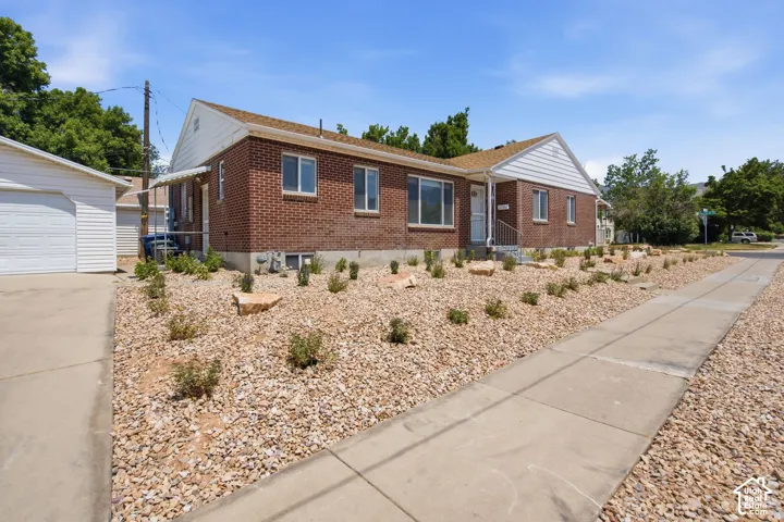 Brick exterior home featuring a covered front porch, white siding gable, and a low-maintenance rock landscape with planted shrubs