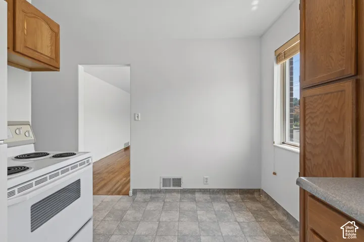 Kitchen area featuring tile flooring, white walls, and a window with blinds