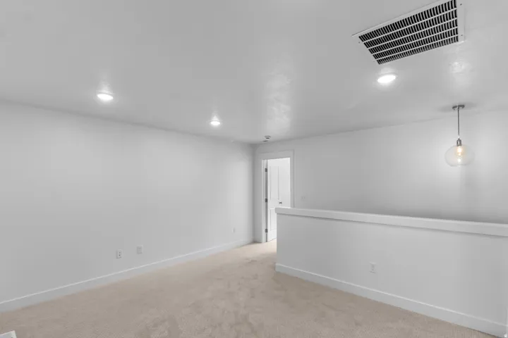 Empty room with light carpet and recessed lighting