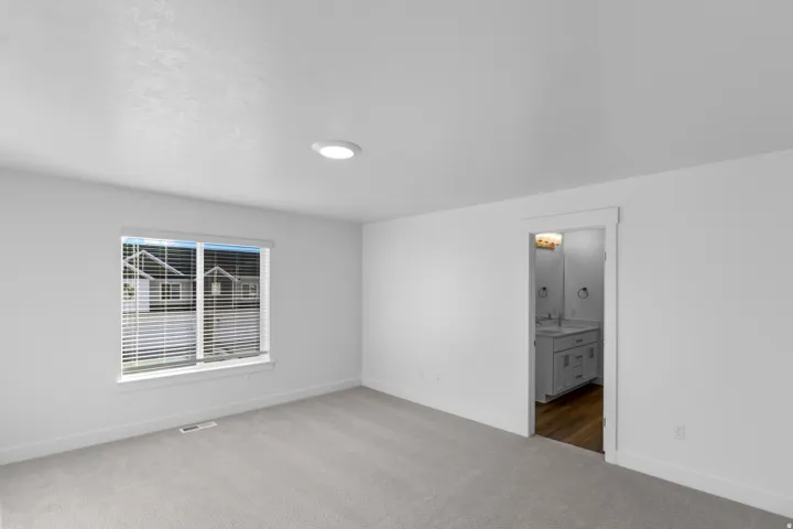Unfurnished bedroom featuring carpet and ensuite bath