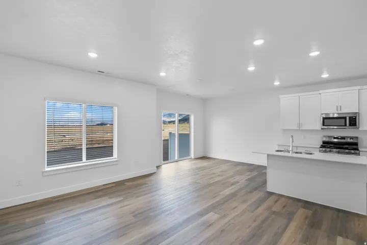 Kitchen with white cabinets, stainless steel appliances, dark wood-type flooring, recessed lighting, and open floor plan