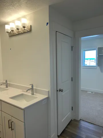 Bathroom featuring double vanity, dark wood-style floors, and a textured ceiling