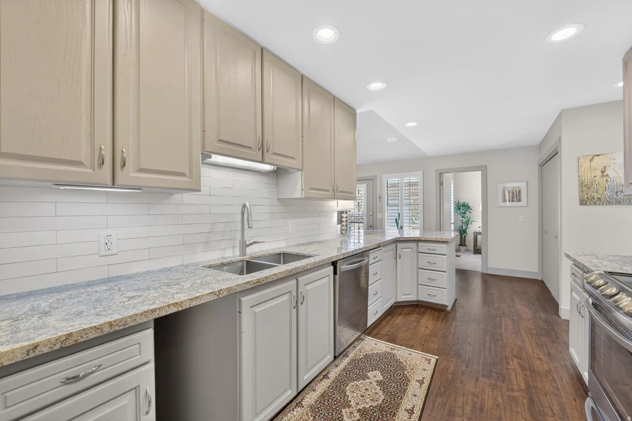 Kitchen featuring light stone counters, stainless steel appliances, dark wood-type flooring, recessed lighting, and a peninsula
