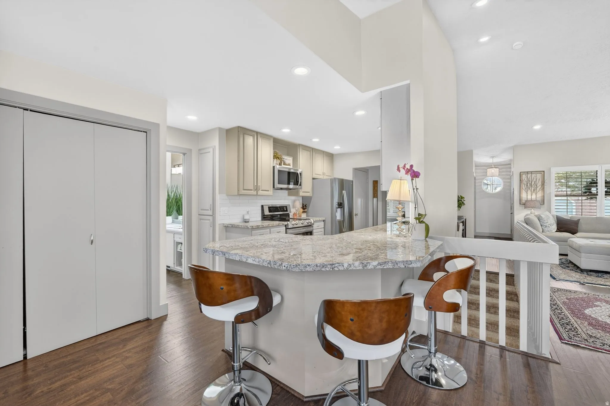 Kitchen with a breakfast bar, stainless steel appliances, open floor plan, dark wood finished floors, and recessed lighting
