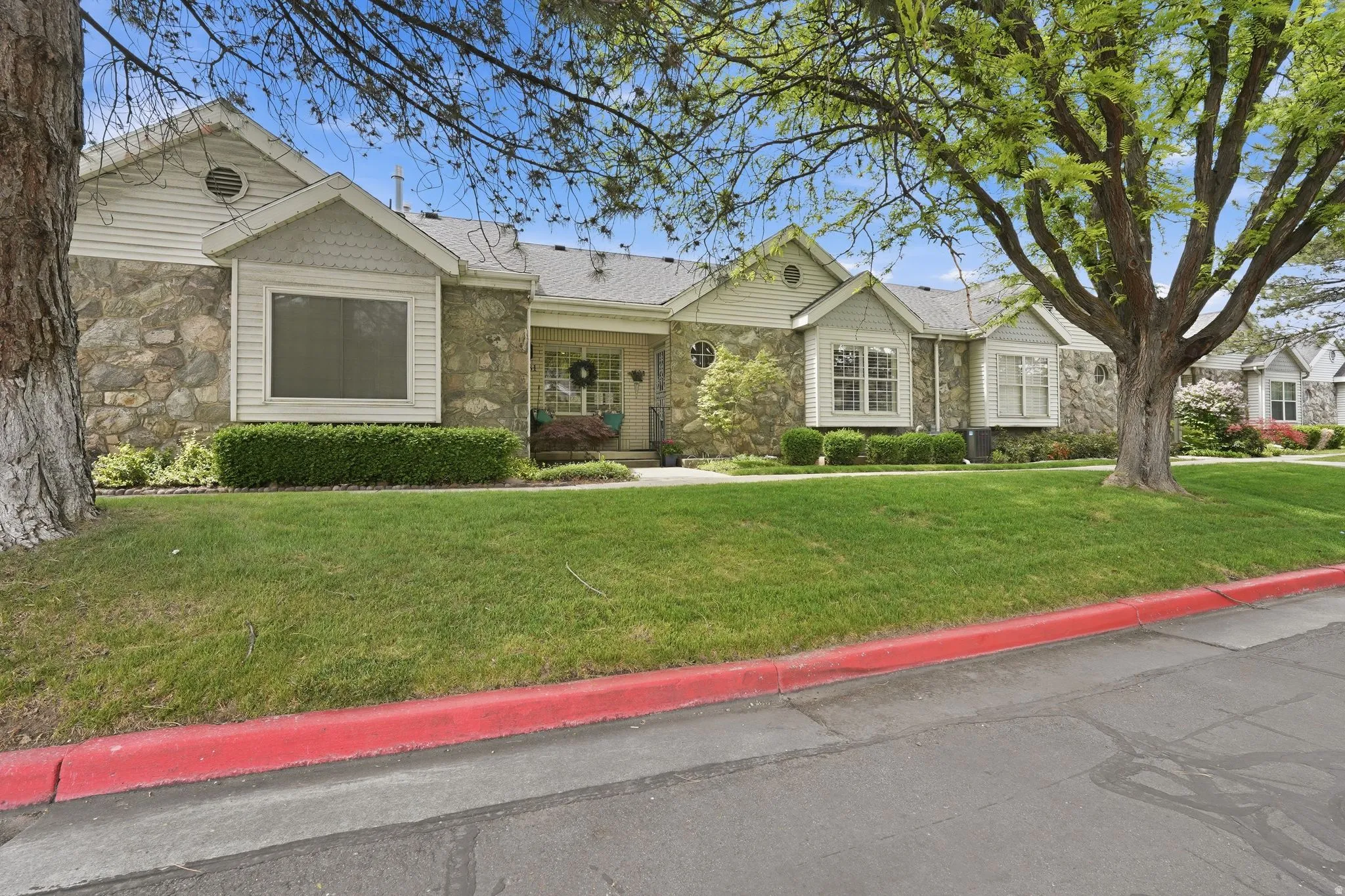 Ranch-style house featuring stone siding and a front lawn