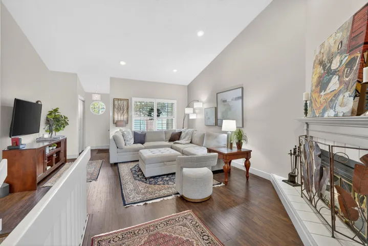 Living room featuring a tile fireplace, dark wood finished floors, vaulted ceiling, and recessed lighting