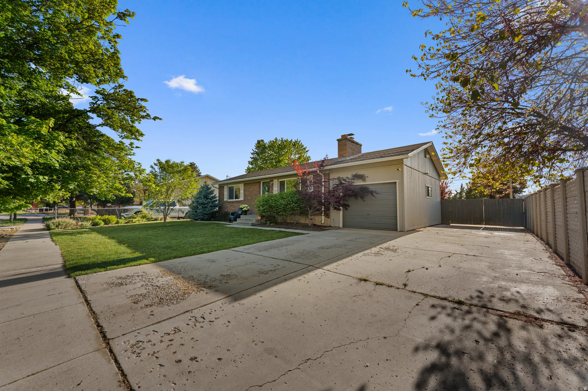 View of front of house with concrete driveway, an attached garage, a chimney, and brick siding