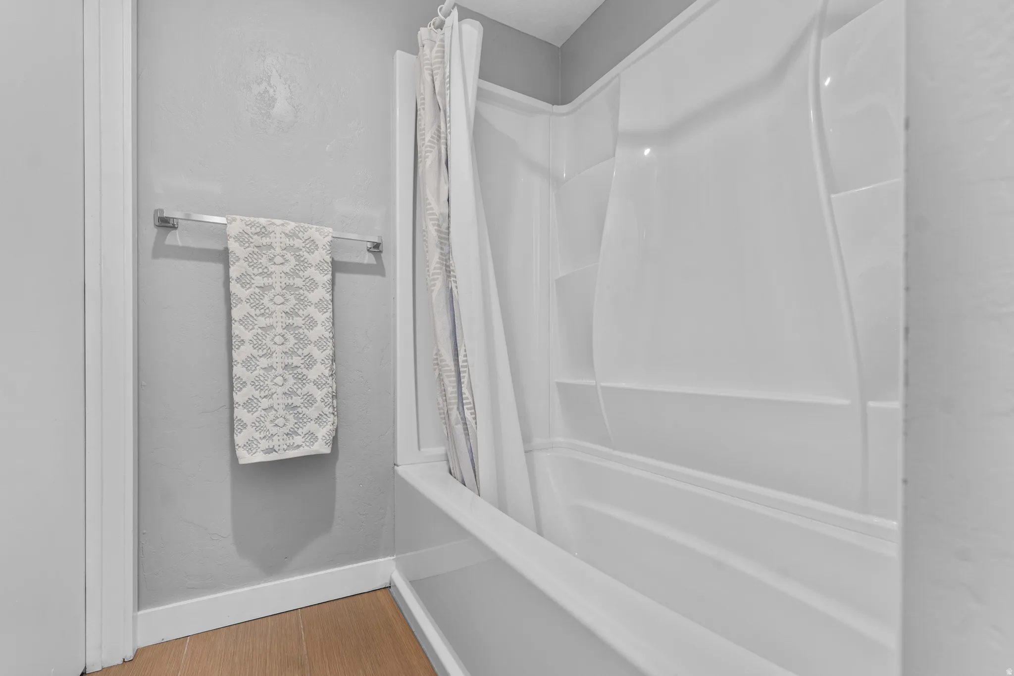 Full bath featuring shower / bathtub combination with curtain and light wood-style flooring