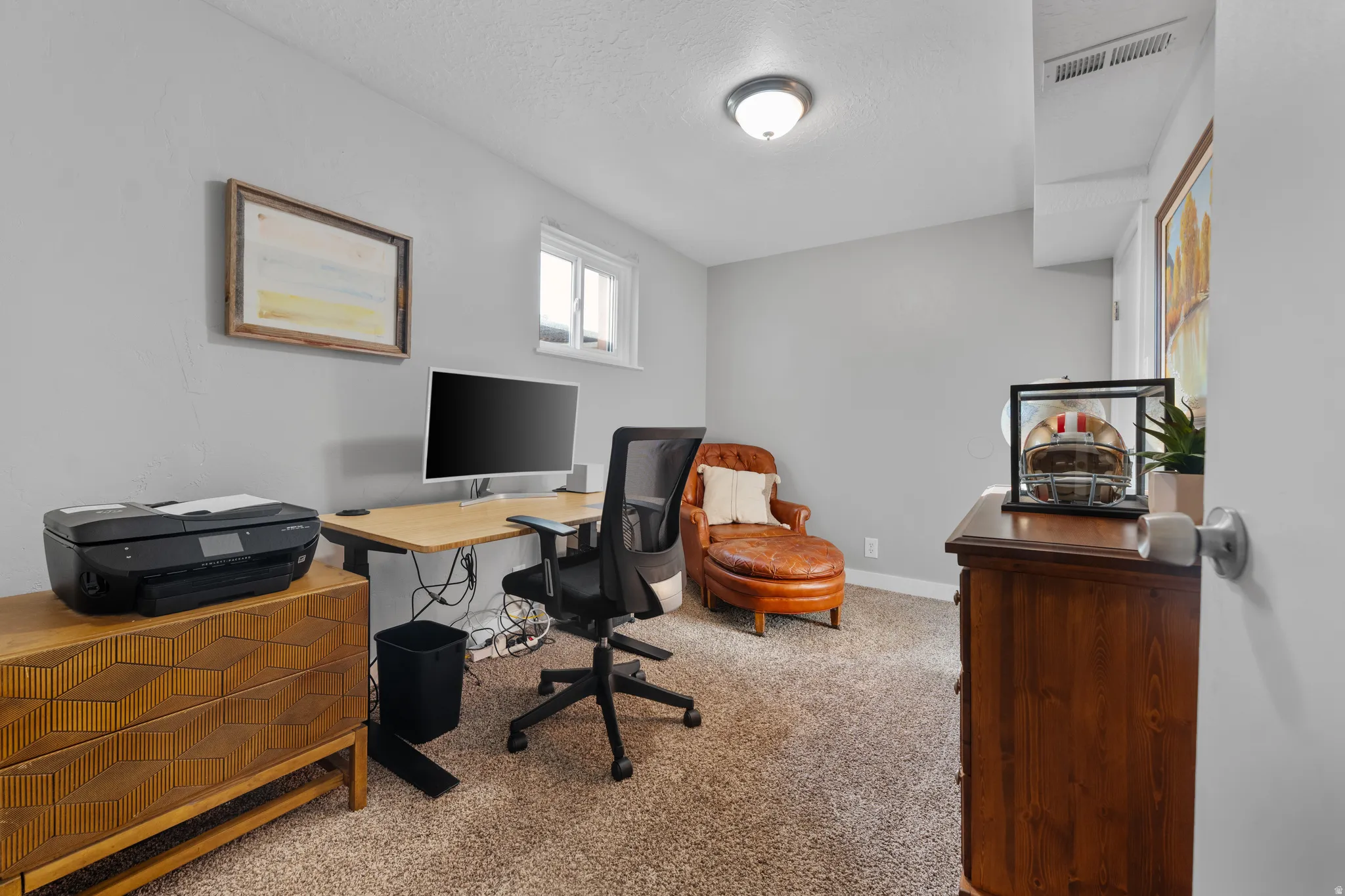 Office with light colored carpet and a textured ceiling