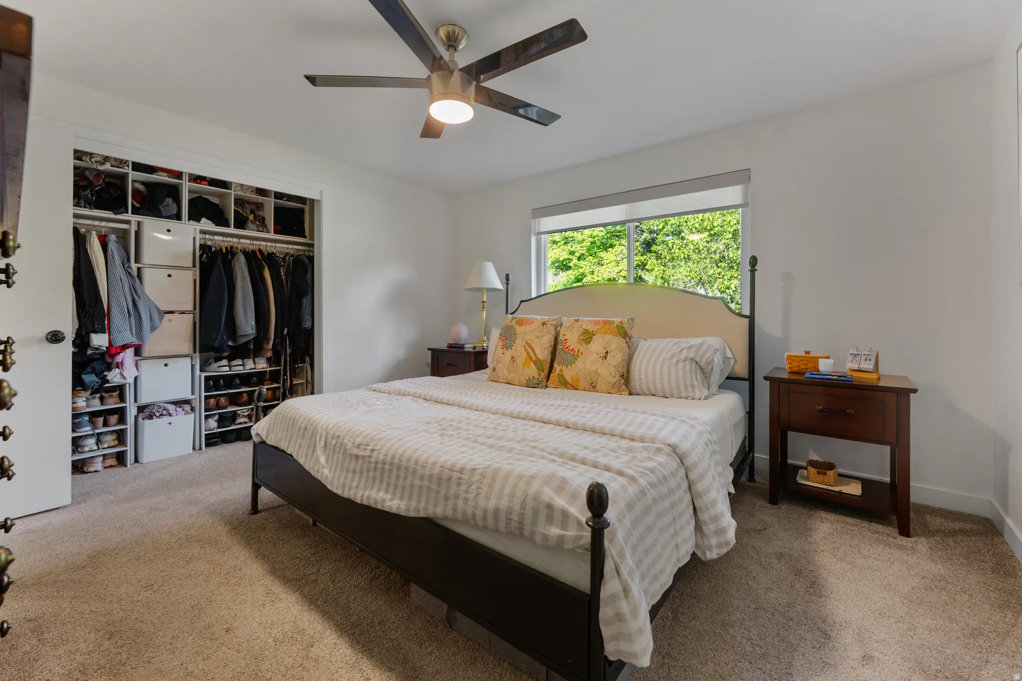 Carpeted bedroom with ceiling fan and a closet