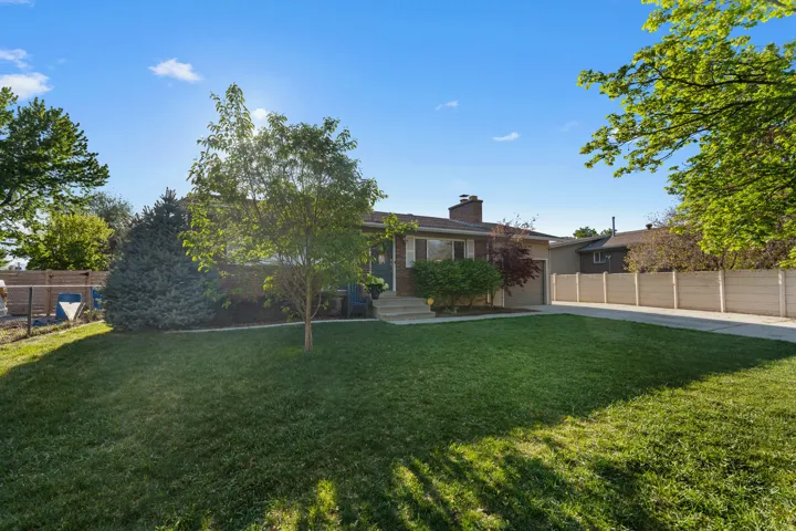 Back of house featuring a chimney, concrete driveway, and an attached garage