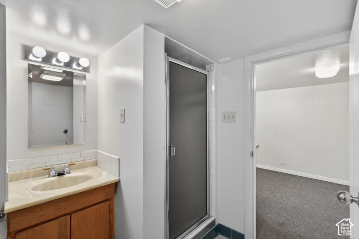 Bathroom featuring vanity, a stall shower, and carpet