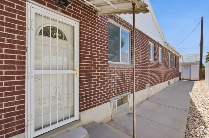 Brick exterior featuring multiple windows and a white security screen door with decorative scrollwork