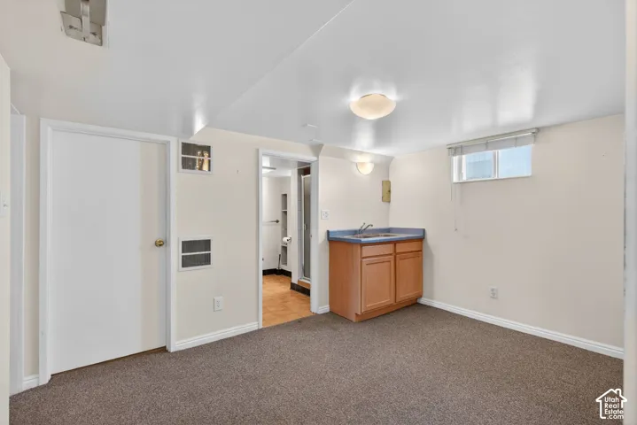 Basement featuring light colored carpet and baseboards