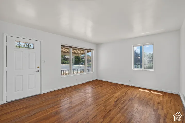 Spacious room featuring wood-finish flooring and white painted walls