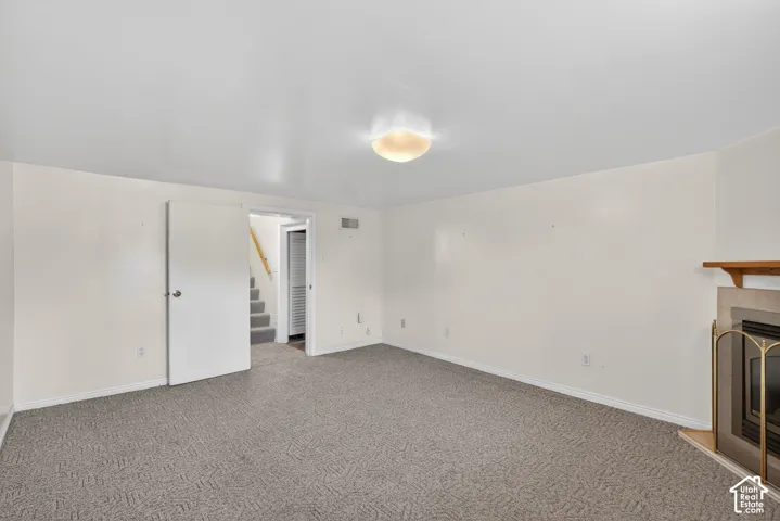 Unfurnished living room featuring a tiled fireplace and carpet
