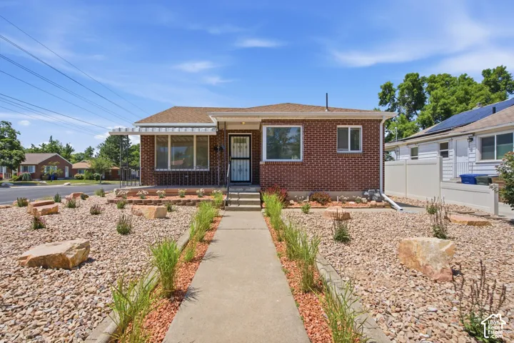 Brick exterior with a brown shingle roof and a concrete walkway