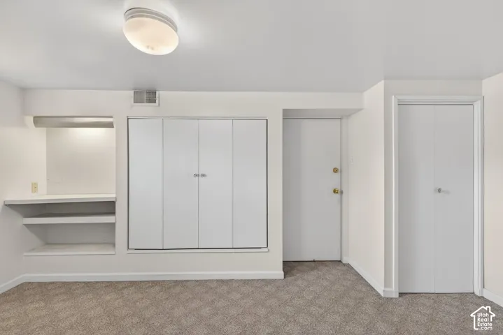 Unfurnished bedroom featuring light carpet and baseboards