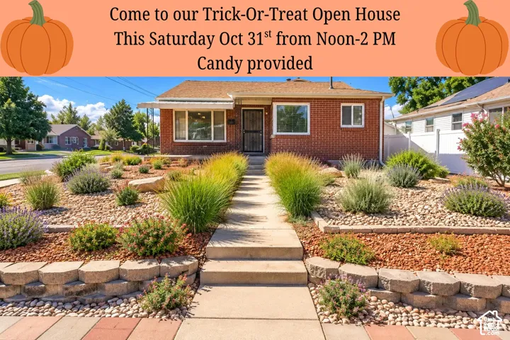 Brick exterior featuring a concrete walkway, tiered stone retaining walls, and xeriscaped garden beds with ornamental grasses and gravel mulch